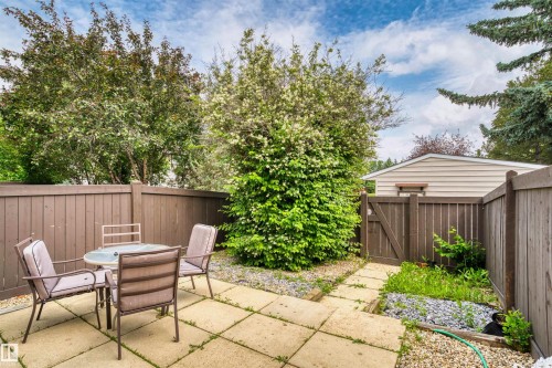 Private outdoor patio space featuring concrete paver flooring, perimeter wood fencing, and a wooden gate - 173 Tudor Lane, Edmonton, AB 