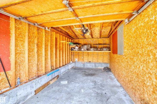 Garage interior featuring oriented strand board walls and ceiling, concrete flooring, and an exposed ceiling structure - 173 Tudor Lane, Edmonton, AB 