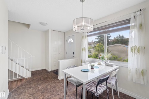 Dining area with a large window, a modern chandelier, and durable flooring - 173 Tudor Lane, Edmonton, AB 