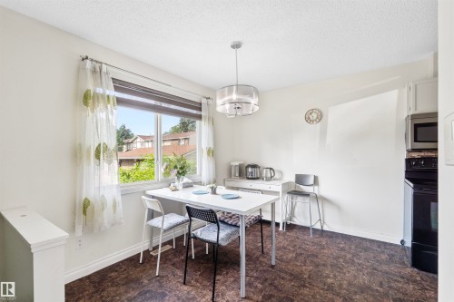 Dining area featuring a large window, dark wood-finish flooring, and a contemporary pendant light fixture - 173 Tudor Lane, Edmonton, AB 