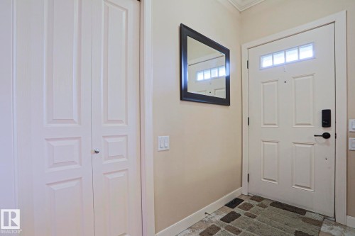 Entryway featuring a white paneled front door with transom windows, a biometric lock, and a dark bronze handle - 13 7293 South Terwillegar Drive, Edmonton, AB 