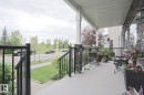 Covered front porch featuring a stone facade, white support columns, and black metal railings - 13 7293 South Terwillegar Drive, Edmonton, AB 