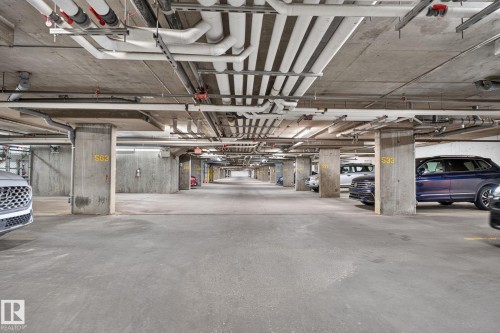 Underground parking garage featuring concrete pillars, concrete flooring, and exposed utility piping - 205 11816 22 Avenue, Edmonton, AB 