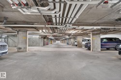 Underground parking garage featuring concrete pillars, concrete flooring, and exposed utility piping - 