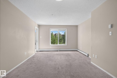 Spacious room featuring neutral paint, light gray carpet, and white baseboards - 205 11816 22 Avenue, Edmonton, AB 