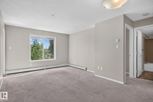 Spacious room with plush carpeting and neutral wall tones - 205 11816 22 Avenue, Edmonton, AB 