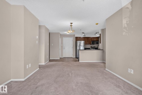Open-concept living area with neutral carpeting and paint - 205 11816 22 Avenue, Edmonton, AB 