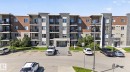 Contemporary multi-story building featuring stacked balconies and a stone and wood-look facade - 205 11816 22 Avenue, Edmonton, AB 
