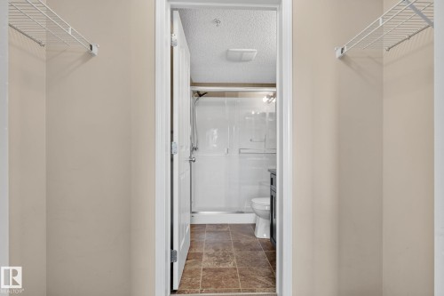Recessed shower stall with sliding glass door, white toilet, and dark wood-finish vanity - 205 11816 22 Avenue, Edmonton, AB 