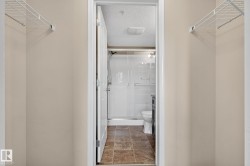 Recessed shower stall with sliding glass door, white toilet, and dark wood-finish vanity - 