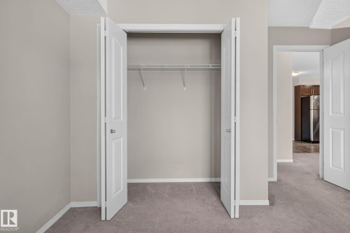 Closet featuring bi-fold doors, wire shelving, and neutral wall paint - 205 11816 22 Avenue, Edmonton, AB 