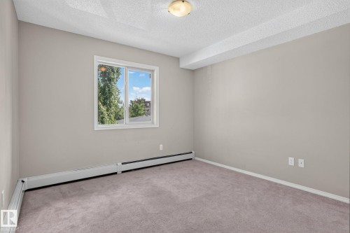Neutral-toned walls and plush carpeting complement the natural light from the window - 205 11816 22 Avenue, Edmonton, AB 