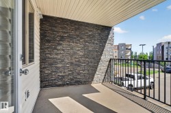 Exterior balcony featuring a stacked stone accent wall, concrete flooring, and a black metal railing - 