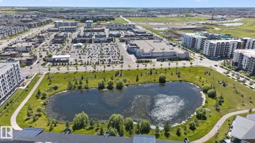 Expansive urban landscape featuring a large central pond surrounded by green space and paved walking paths - 205 11816 22 Avenue, Edmonton, AB 