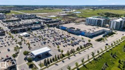Expansive retail center featuring a large asphalt parking area, surrounding commercial buildings, and multi-story residential structures - 