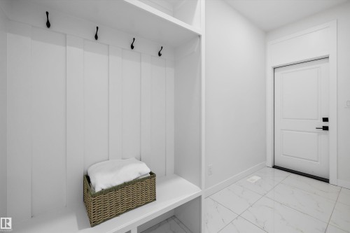 Built-in mudroom bench with upper storage and black wall-mounted hooks - 403 Pine Point, Leduc, AB 
