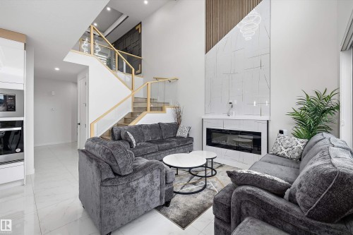 Grand living area featuring a two-story ceiling, a contemporary fireplace with a large-format tile surround, and a dramatic wood-slat accent wall - 403 Pine Point, Leduc, AB 