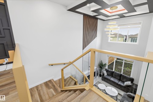 Grand staircase with wood-finish treads and glass railings - 403 Pine Point, Leduc, AB 