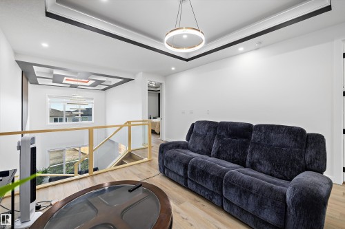 Open concept upper-level area featuring light wood-finish flooring, recessed lighting, and a modern ceiling fixture - 403 Pine Point, Leduc, AB 
