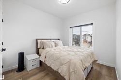 Bright room featuring wood-finish flooring, a contemporary window with blinds, and white baseboards - 