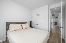 White walls, wood-finish flooring, and white bi-fold closet doors with black hardware - 