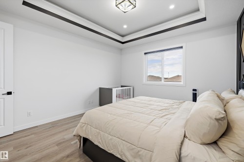 Recessed lighting illuminating a tray ceiling with dark accent trim, wood-finish flooring, and a single window - 403 Pine Point, Leduc, AB 