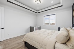 Recessed lighting illuminating a tray ceiling with dark accent trim, wood-finish flooring, and a single window - 