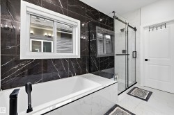 Contemporary bathroom featuring a built-in soaking tub with matte black fixtures, a spacious glass-enclosed shower with a sliding door, and a striking black and white marble-look tile surround - 