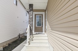 Front entrance featuring a brown door with clear glass panels, concrete steps, and a white handrail - 