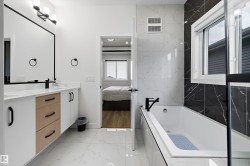 Contemporary bathroom featuring a combined shower and bathtub with matte black fixtures, white marble-look tile flooring, and a vanity with white cabinetry, wood-finish drawers, and a white countertop - 