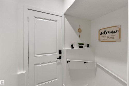 White paneled door with matte black hardware, featuring a contemporary smart lock system - 403 Pine Point, Leduc, AB 