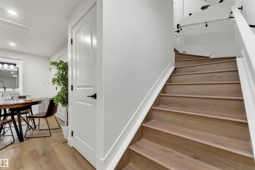 Staircase featuring wood-finish treads and white risers with a contrasting white handrail - 403 Pine Point, Leduc, AB 