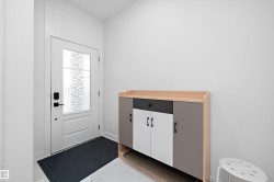 Entryway featuring a white paneled door with decorative glass, modern black hardware, and a transom window above - 