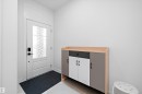 Entryway featuring a white paneled door with decorative glass, modern black hardware, and a transom window above - 403 Pine Point, Leduc, AB 