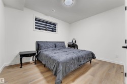 Room featuring wood-finish flooring, white baseboards, and a window with horizontal blinds - 