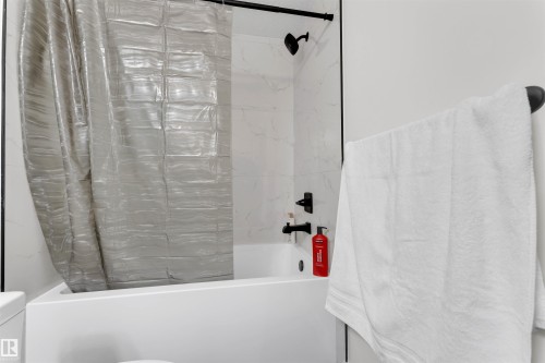 Bathtub with subway tile surround, matte black fixtures, and a coordinating towel bar - 403 Pine Point, Leduc, AB 