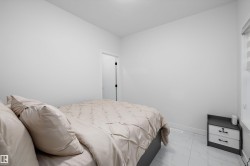 Bright room featuring white walls, white tile flooring, a window with horizontal blinds, and a white baseboard - 
