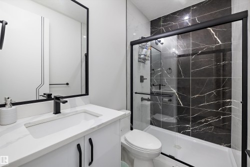 Bathroom featuring a white vanity with an integrated sink, a quartz-finish countertop, and matte black fixtures - 403 Pine Point, Leduc, AB 