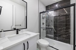 Bathroom featuring a white vanity with an integrated sink, a quartz-finish countertop, and matte black fixtures - 