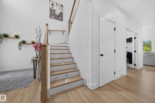 Modern staircase featuring light wood-finish treads, white risers with subtle veining, and integrated step lighting - 626 Astoria Way, Devon, AB 