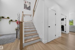 Modern staircase featuring light wood-finish treads, white risers with subtle veining, and integrated step lighting - 