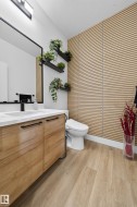 Contemporary bathroom featuring a wood-finish vanity with a white countertop and matte black hardware - 