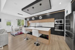 Contemporary kitchen featuring a large island with white countertop, rich dark cabinetry, light wood-finish accents, and stainless steel appliances - 