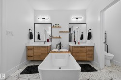 Contemporary bathroom featuring a freestanding soaking tub, dual floating wood-finish vanities with quartz countertops, and black-framed mirrors - 