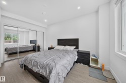 Bedroom featuring wood-finish flooring, recessed lighting, white walls, a window with a roller shade, and sliding mirrored closet doors - 