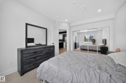 Recessed lighting illuminates this bright room featuring wood-finish flooring and a spacious mirrored closet - 