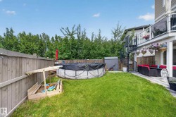 Expansive backyard featuring a manicured lawn, a full wooden fence, and mature trees providing privacy - 