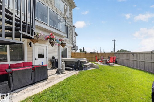 Expansive outdoor space featuring a manicured lawn, a paved patio area, and a built-in hot tub - 626 Astoria Way, Devon, AB 