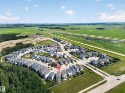 Aerial perspective showcasing a residential community with contemporary homes, bordered by expansive green fields and a distant highway - 