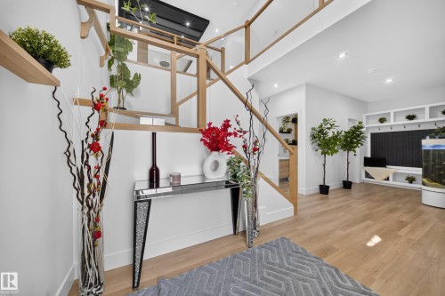 Open-concept entryway featuring a modern staircase with light wood railings and glass panels - 626 Astoria Way, Devon, AB 